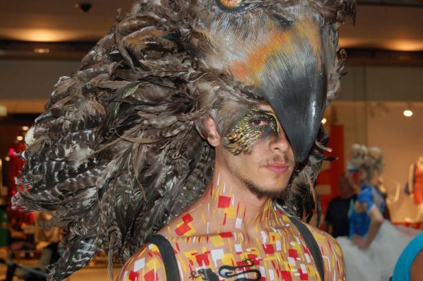 Ein Mann mit aufwendigem Eulenkostüm und Körperbemalung.