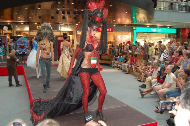 Eine Modenschau mit extravaganten Kostümen und Bodypainting vor Publikum.