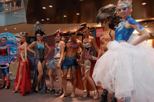 Eine Gruppe von Models präsentiert extravagante Mode und Körperbemalung auf einem Laufsteg.