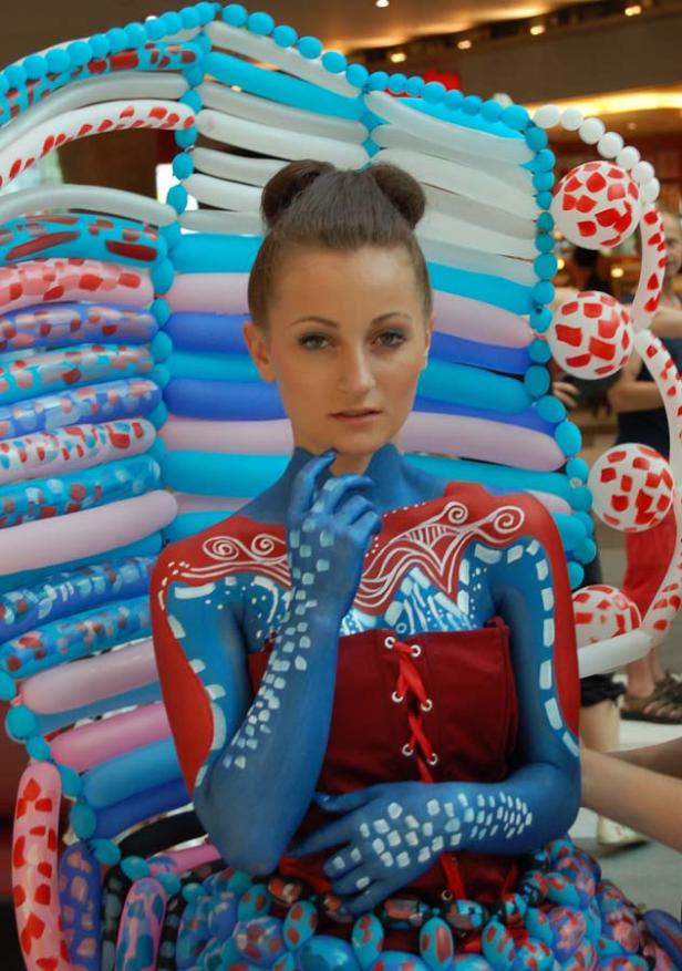 Eine Frau mit Körperbemalung und einem Kostüm aus Ballons posiert für ein Foto.