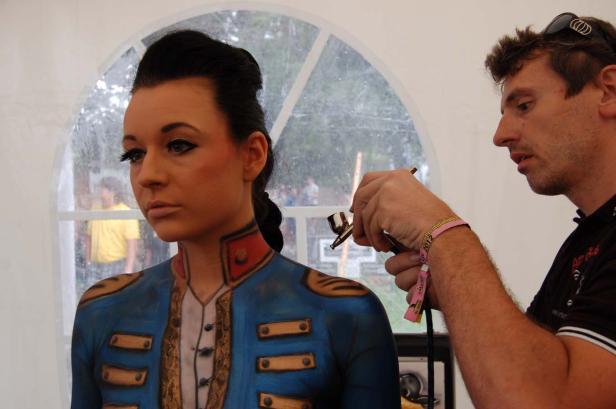 Eine Frau erhält ein aufwendiges Körperbemalung im Stil einer historischen Uniform.