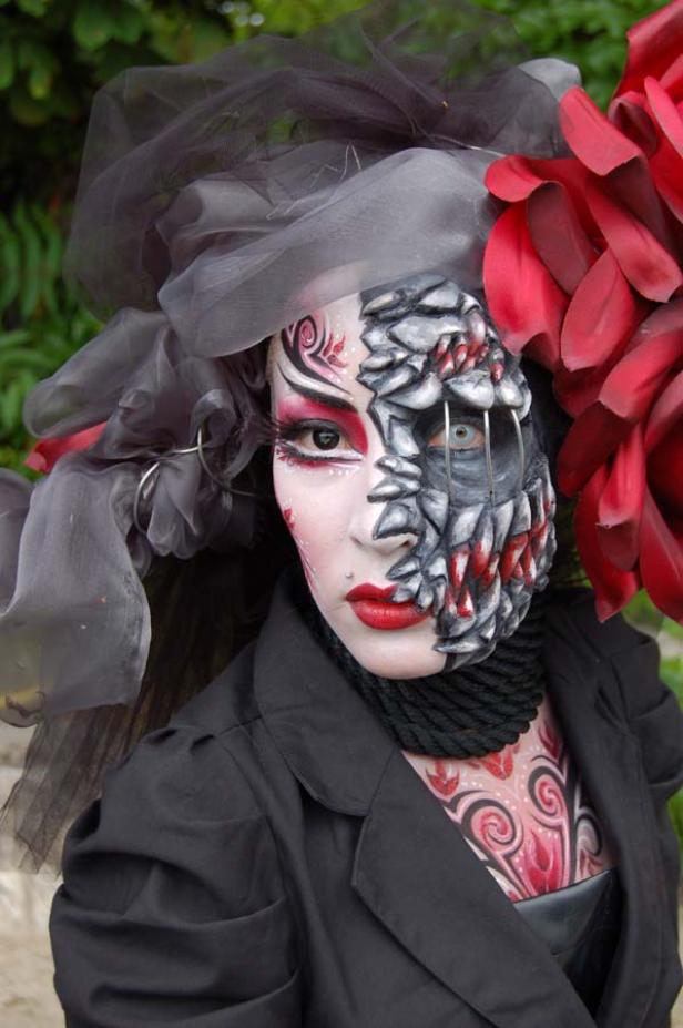 Eine Person mit aufwendigem Make-up, das eine Hälfte des Gesichts als Monster darstellt.