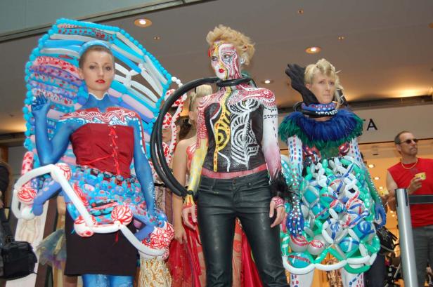 Drei Frauen präsentieren extravagante Körperbemalung und Kostüme aus Ballons.