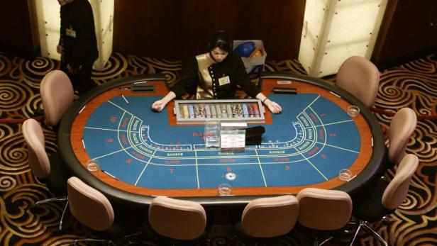 Eine Croupier sitzt an einem Baccarat-Tisch in einem Kasino.