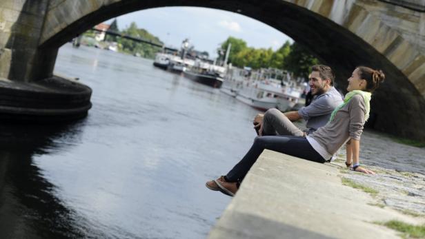 Ein Paar sitzt unter einer Brücke am Flussufer und genießt die Aussicht.