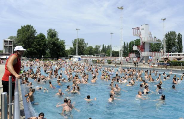 Ein Freibad ist an einem sonnigen Tag mit vielen Menschen gefüllt.