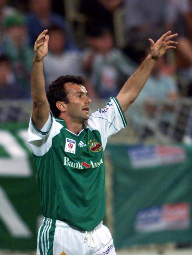 Ein Fußballspieler in Grün und Weiß jubelt mit erhobenen Armen.
