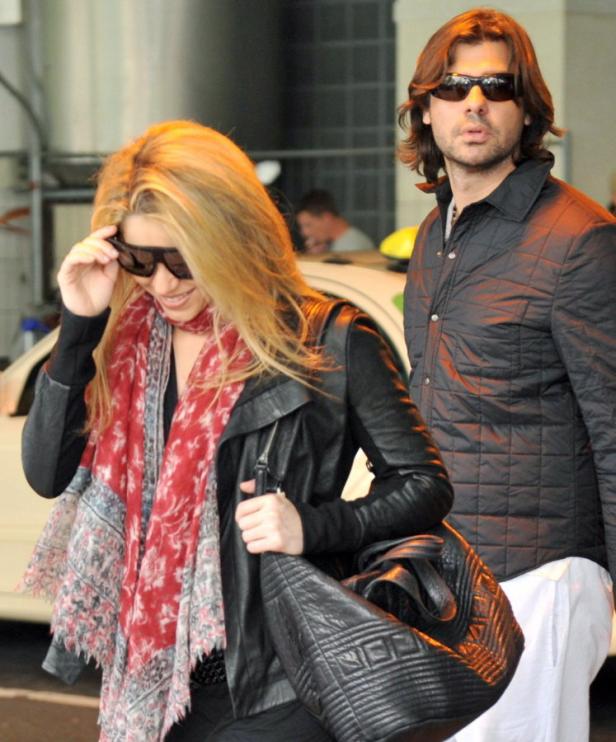 Shakira und ihr Partner verlassen ein Gebäude mit einer schwarzen Lederjacke und Sonnenbrillen.