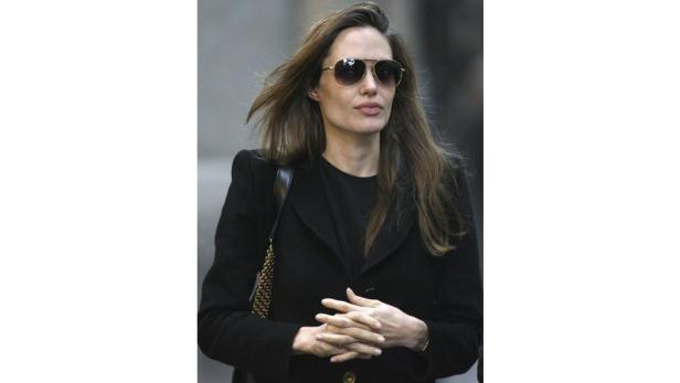Angelina Jolie mit Sonnenbrille und schwarzem Mantel.