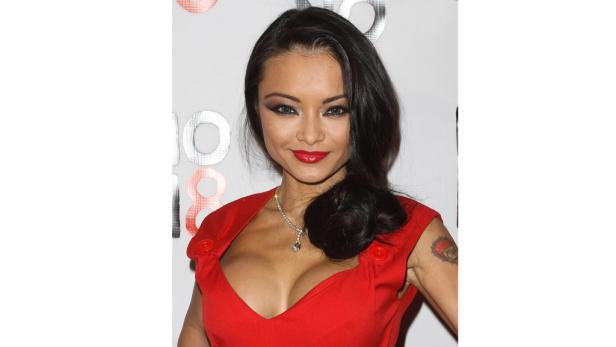 Eine Frau mit dunklen Haaren und rotem Kleid lächelt in die Kamera.