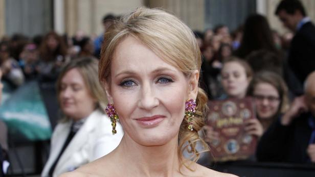 J.K. Rowling posiert mit auffälligen Ohrringen vor einer Menschenmenge.