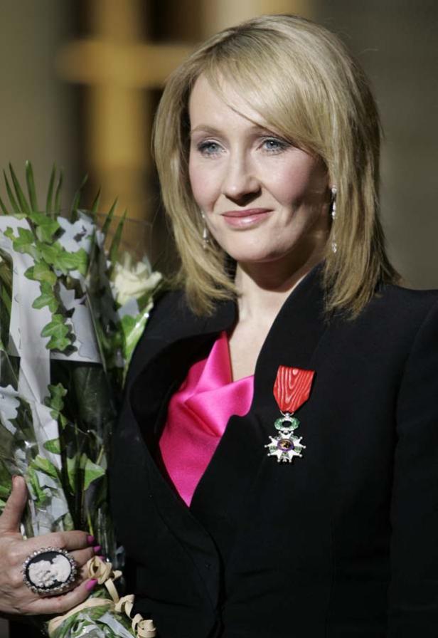 J.K. Rowling mit einem Blumenstrauß und einem Orden an ihrem Blazer.