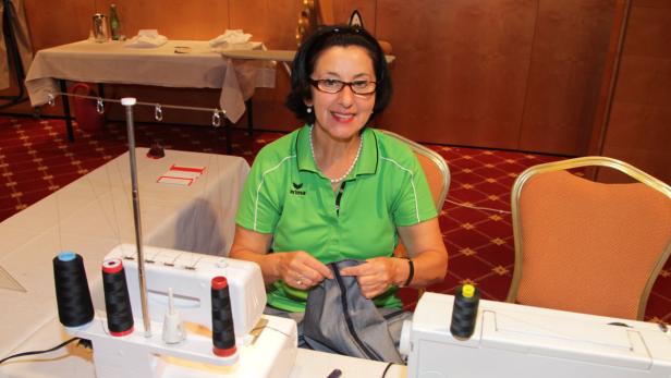 Eine Frau mit Brille näht an einer Nähmaschine.