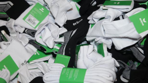 Ein Haufen neuer, verpackter Socken der Marke Erima in Schwarz und Weiß.