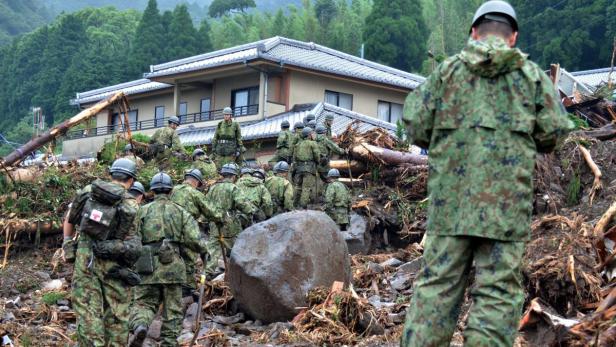 Soldaten in Tarnuniformen räumen nach einer Naturkatastrophe Trümmer weg.