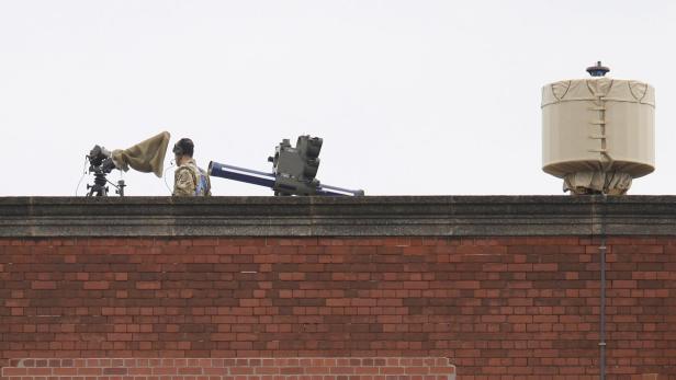 Ein Soldat mit Überwachungsgeräten und einem Raketenwerfer auf einem Dach.