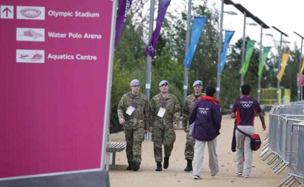 Drei Soldaten gehen an einem Schild zu den Sportstätten des Olympiaparks London vorbei.