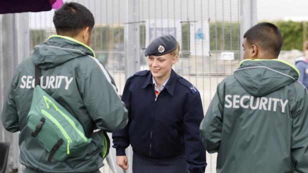 Eine Frau in Uniform spricht mit zwei Sicherheitsleuten.