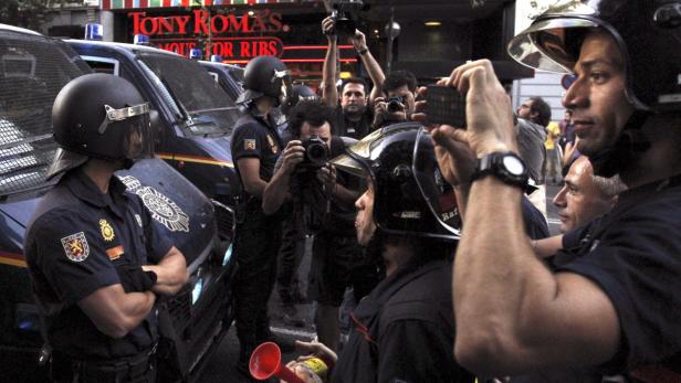 Polizisten und Feuerwehrleute stehen vor einem Tony Roma's Restaurant, während Fotografen Fotos machen.