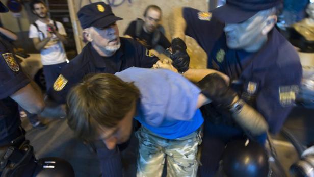 Polizisten nehmen eine Person in einem unruhigen Umfeld fest.