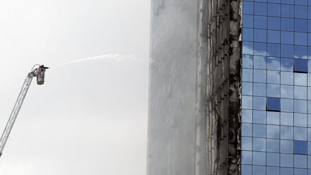 Ein Feuerwehrmann löscht mit einem Wasserstrahl ein brennendes Gebäude.