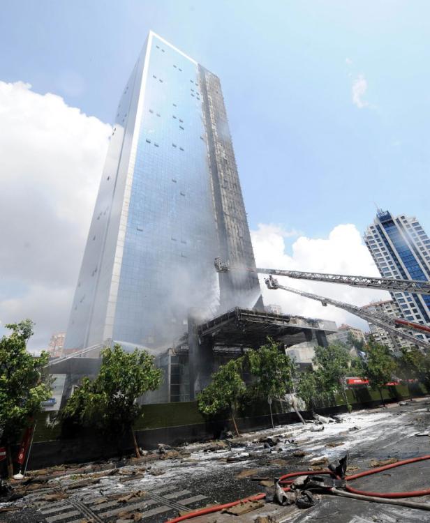 Ein Hochhaus steht in Flammen, während Feuerwehrleute versuchen, das Feuer zu löschen.
