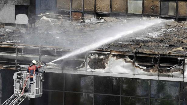Ein Feuerwehrmann löscht ein Feuer in einem beschädigten Gebäude.