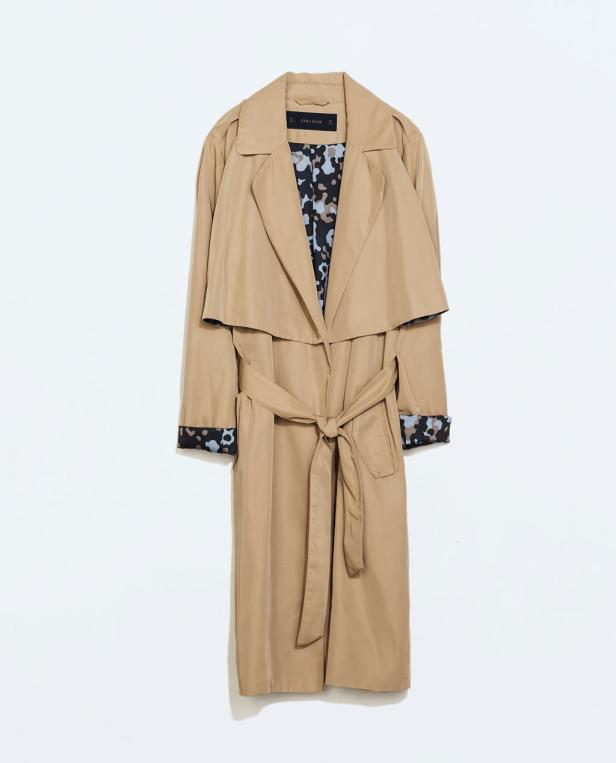 Ein beigefarbener Trenchcoat mit Gürtel vor einem weißen Hintergrund.