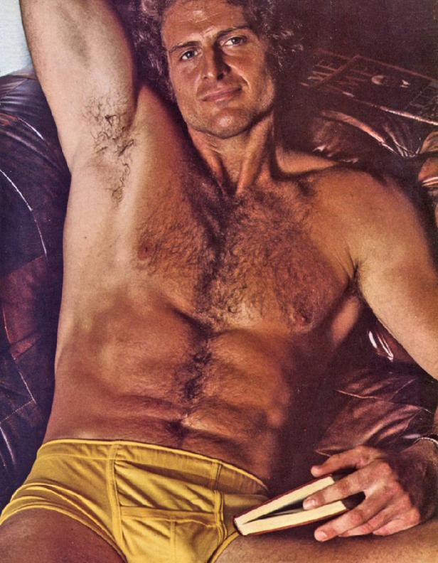 Ein Mann liegt auf einer Couch und hält ein Buch in der Hand.