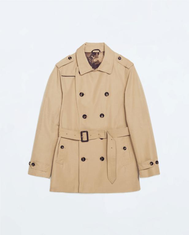 Ein beigefarbener Trenchcoat mit Gürtel und dunklen Knöpfen vor einem weißen Hintergrund.