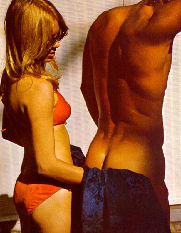 Eine Frau im roten Bikini steht neben einem Mann mit einem Handtuch um die Hüfte.