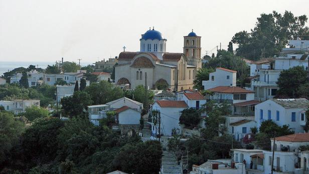 Ein griechisches Dorf mit weißen Häusern und einer Kirche mit blauer Kuppel.