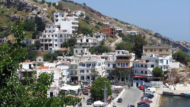 Blick auf eine griechische Stadt mit weißen Häusern an einem Hang.