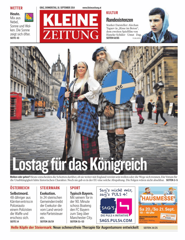 Zwei Personen in schottischer Tracht stehen vor einem Gebäude in einer Stadt.