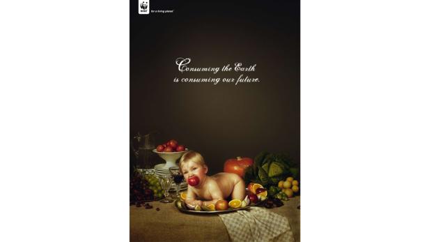 Ein Baby liegt auf einem Silbertablett inmitten von Obst und Gemüse.