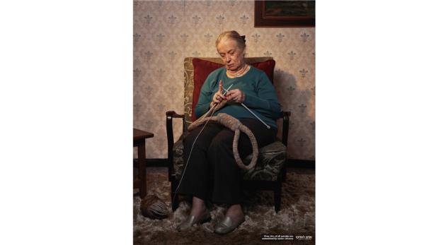 Eine ältere Frau strickt eine Schlinge aus Wolle.