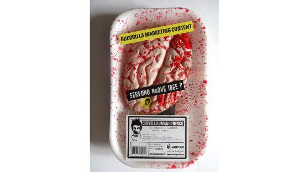 Ein Gehirn in einer Plastikverpackung, bedeckt mit roter Farbe, mit dem Text „Guerrilla Marketing Content“.