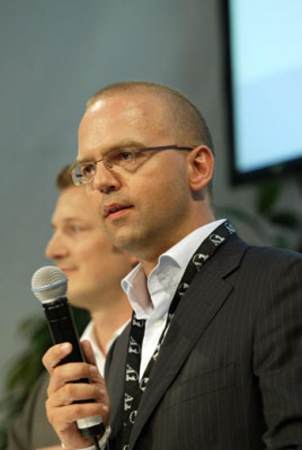 Ein Mann mit Brille hält ein Mikrofon und spricht.