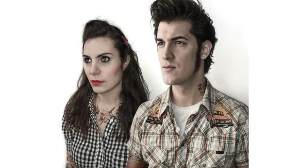 Ein Paar im Rockabilly-Stil mit Tattoos und karierten Hemden vor einem weißen Hintergrund.