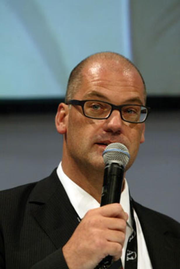 Ein Mann mit Brille spricht in ein Mikrofon.