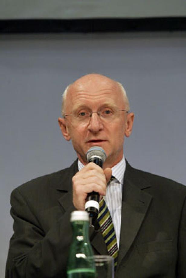 Ein Mann mit Brille und Anzug spricht in ein Mikrofon.