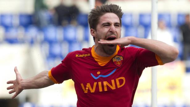 Ein Fußballspieler im roten Trikot jubelt mit erhobenen Armen.