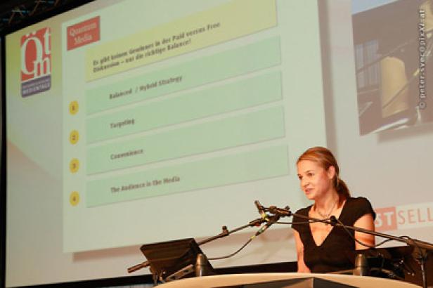 Eine Frau hält eine Präsentation auf einer Konferenz vor einer Leinwand.