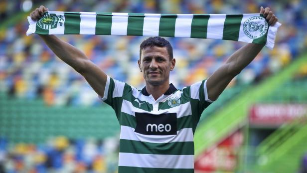 Ein Mann im Trikot von Sporting Lissabon hält einen Schal über seinen Kopf.