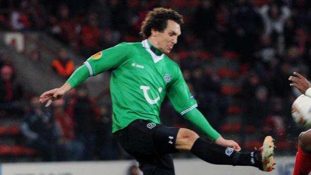 Ein Fußballspieler in einem grünen Trikot von Hannover 96 schießt einen Ball.