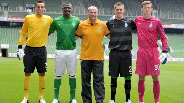 Fünf Männer, vermutlich Torhüter von Werder Bremen, posieren auf dem Rasen des Stadions.
