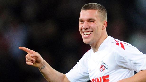 Lukas Podolski im Trikot des 1. FC Köln lächelt und zeigt mit dem Finger.