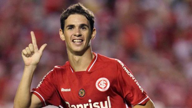 Ein lächelnder Fußballspieler in rotem Trikot zeigt mit dem Finger nach oben.