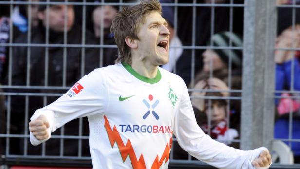 Ein jubelnder Fußballspieler im Trikot von Werder Bremen.