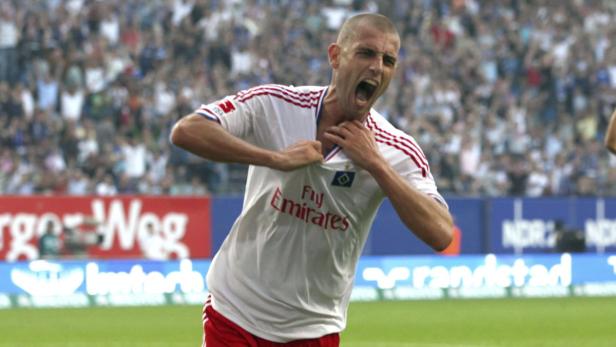 Ein Fußballspieler des Hamburger SV jubelt mit aufgerissenem Trikot vor der Fankurve.